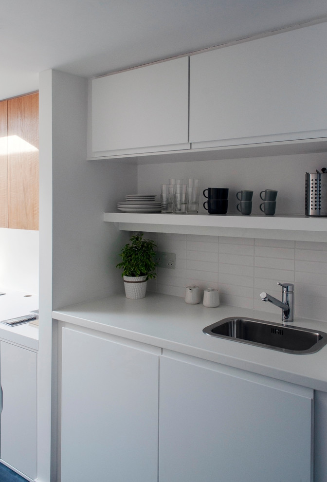 Idéer för små minimalistiska linjära vitt kök med öppen planlösning, med släta luckor, vitt stänkskydd och stänkskydd i keramik