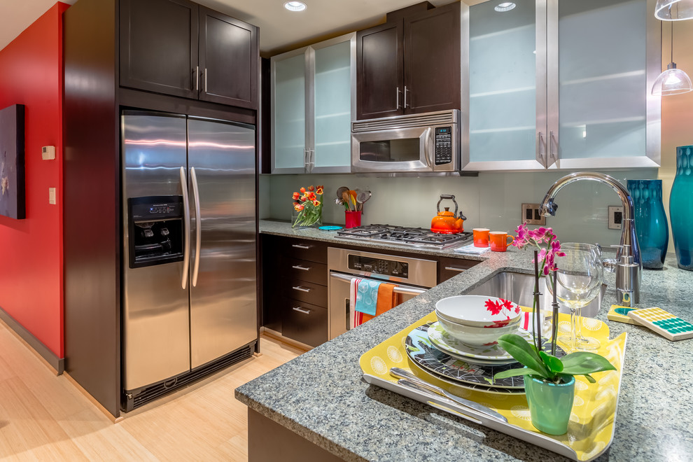 Example of a small trendy u-shaped bamboo floor and yellow floor eat-in kitchen design in Seattle with an undermount sink, glass-front cabinets, black cabinets, granite countertops, green backsplash, glass sheet backsplash, stainless steel appliances and a peninsula