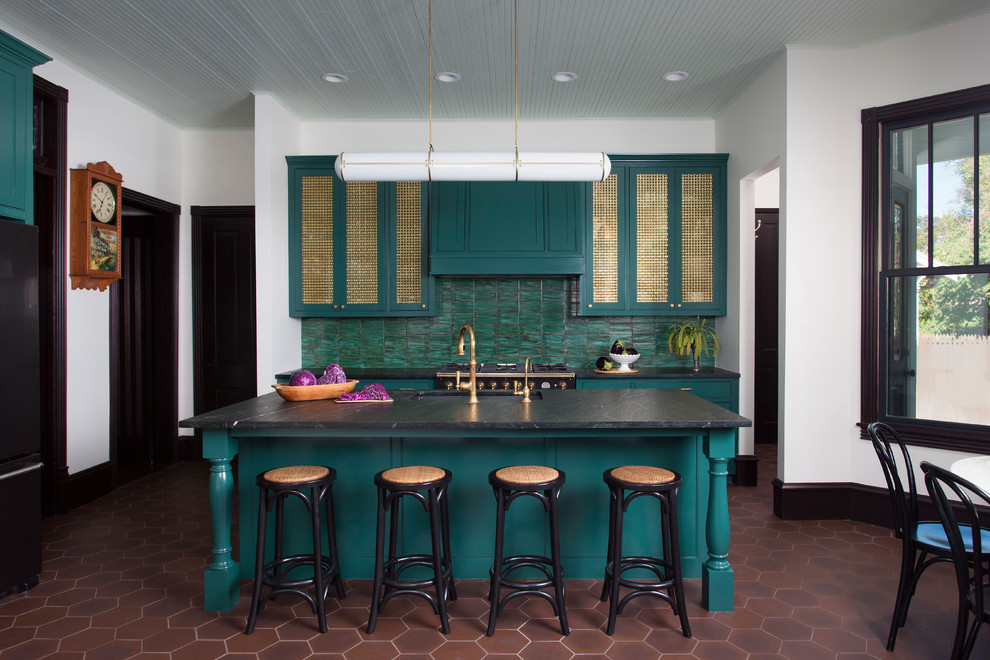 Пример оригинального дизайна: кухня в стиле фьюжн с обеденным столом, врезной мойкой, зелеными фасадами, зеленым фартуком, черной техникой, островом, коричневым полом и окном