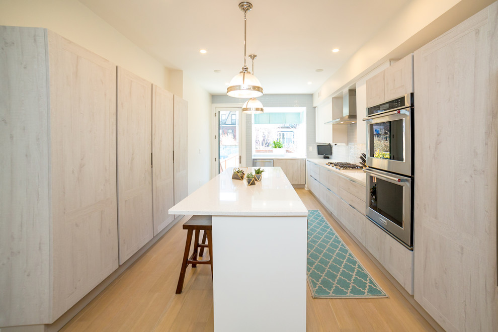 Example of a mid-sized trendy galley light wood floor open concept kitchen design in New York with an undermount sink, beaded inset cabinets, light wood cabinets, quartz countertops, blue backsplash, porcelain backsplash, stainless steel appliances, an island and white countertops