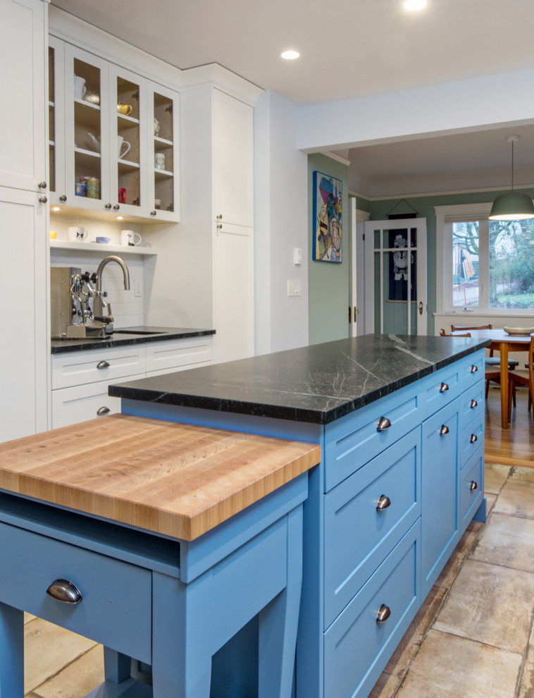 Foto på ett mellanstort amerikanskt kök, med en undermonterad diskho, skåp i shakerstil, blå skåp, bänkskiva i täljsten, flerfärgad stänkskydd, stänkskydd i tunnelbanekakel, rostfria vitvaror, klinkergolv i porslin, en köksö och beiget golv