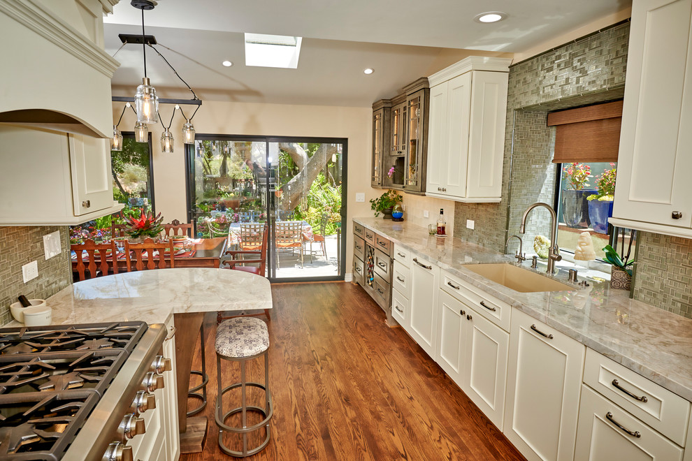Inspiration for a medium sized traditional galley open plan kitchen in San Diego with a submerged sink, recessed-panel cabinets, white cabinets, quartz worktops, white splashback, glass tiled splashback, stainless steel appliances, medium hardwood flooring, no island, brown floors and green worktops.