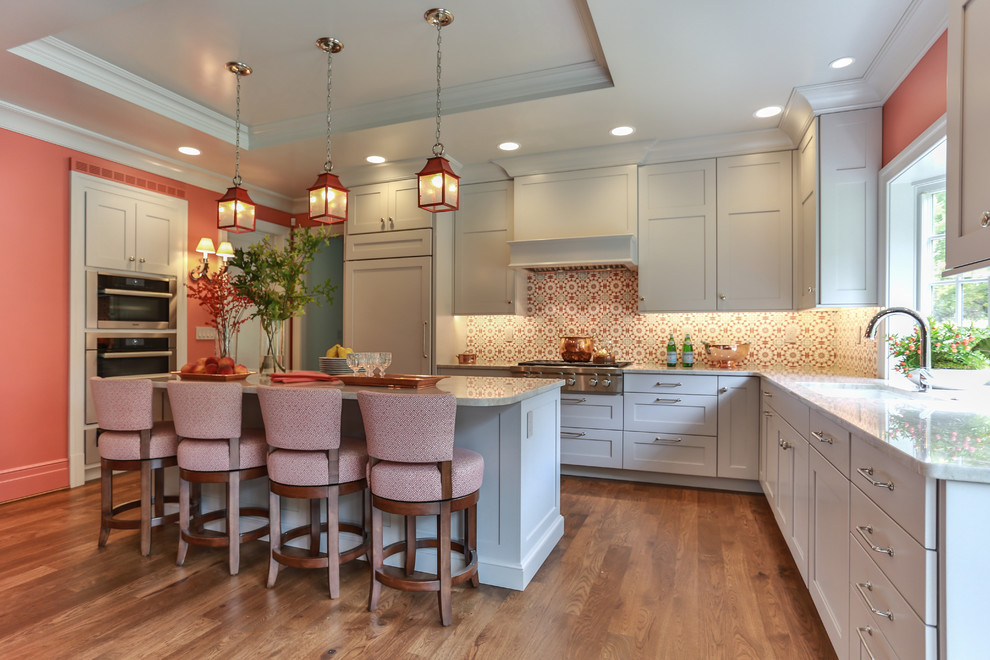 Large transitional u-shaped medium tone wood floor eat-in kitchen photo in Milwaukee with an undermount sink, recessed-panel cabinets, white cabinets, quartzite countertops, multicolored backsplash, terra-cotta backsplash, paneled appliances and an island