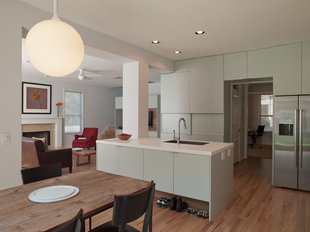 Imagen de cocina moderna abierta con electrodomésticos de acero inoxidable, armarios con paneles lisos y puertas de armario verdes