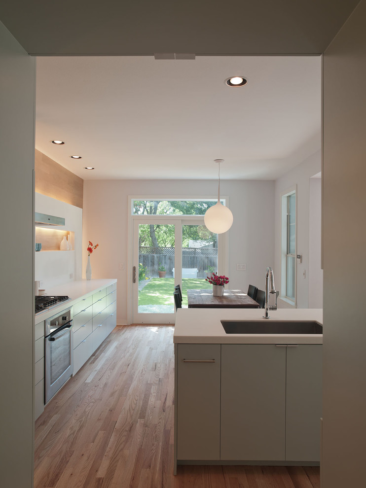 Immagine di una cucina abitabile minimalista con lavello a vasca singola, ante lisce, ante verdi, top in quarzo composito, paraspruzzi bianco e paraspruzzi in lastra di pietra