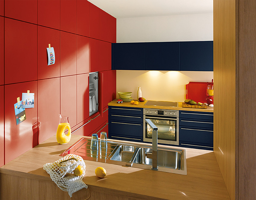 Modelo de cocina moderna de tamaño medio cerrada con fregadero de un seno, armarios con paneles lisos, puertas de armario rojas, encimera de laminado, electrodomésticos de acero inoxidable y península