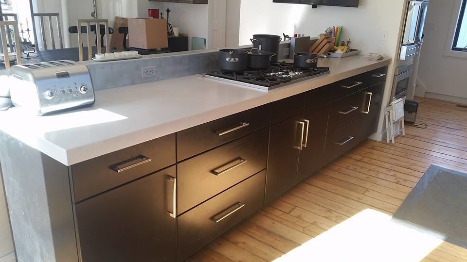 Urban galley kitchen photo in New York with black cabinets, concrete countertops and an island
