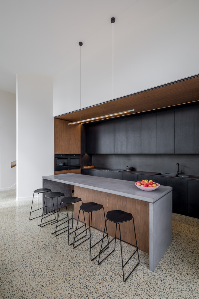 Imagen de cocinas en L moderna con armarios con paneles lisos, puertas de armario negras, una isla, suelo gris y encimeras grises