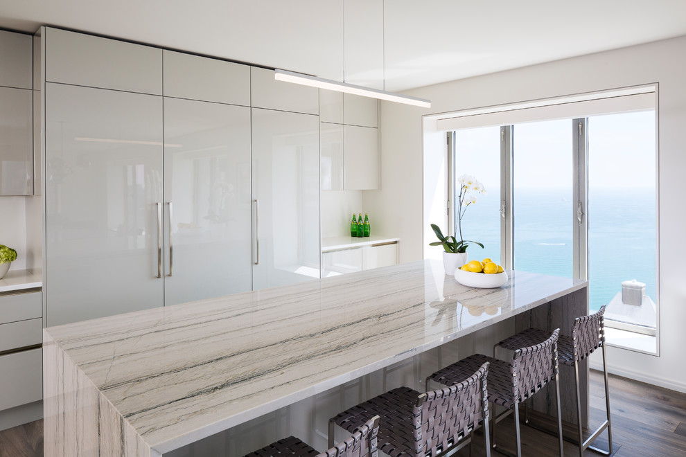 Esempio di un cucina con isola centrale contemporaneo con ante lisce, ante bianche, paraspruzzi bianco, parquet scuro, pavimento marrone e top bianco