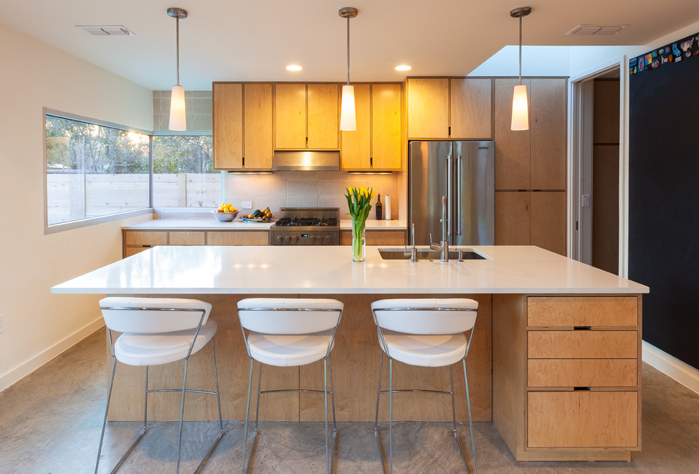 Cette photo montre une cuisine parallèle rétro en bois brun avec un évier encastré, un placard à porte plane, une crédence beige, un électroménager en acier inoxydable et îlot.