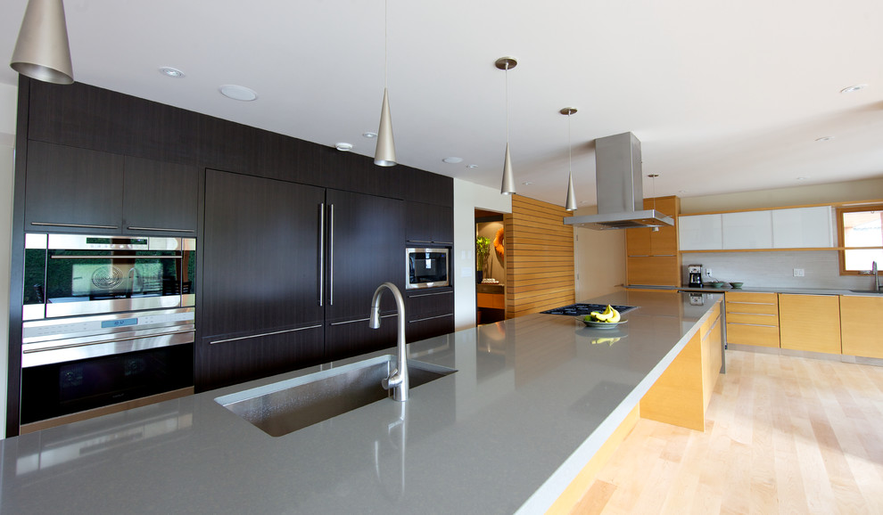 Große Moderne Wohnküche in L-Form mit Unterbauwaschbecken, flächenbündigen Schrankfronten, hellen Holzschränken, Küchengeräten aus Edelstahl, hellem Holzboden und Kücheninsel in Vancouver