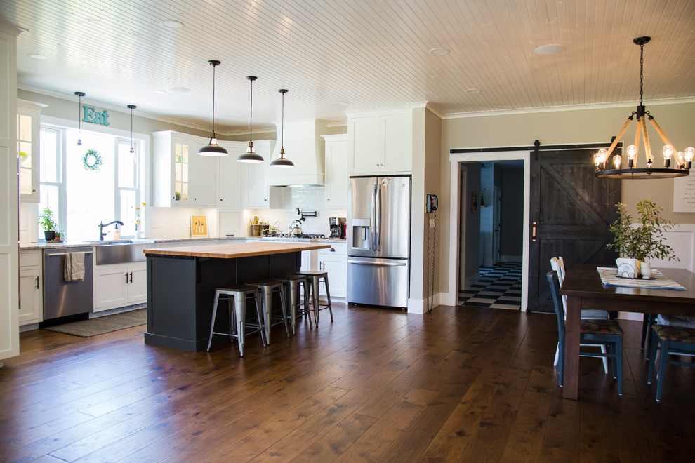Foto på ett stort lantligt flerfärgad kök, med en rustik diskho, luckor med infälld panel, vita skåp, granitbänkskiva, vitt stänkskydd, stänkskydd i keramik, rostfria vitvaror, mellanmörkt trägolv, en köksö och brunt golv