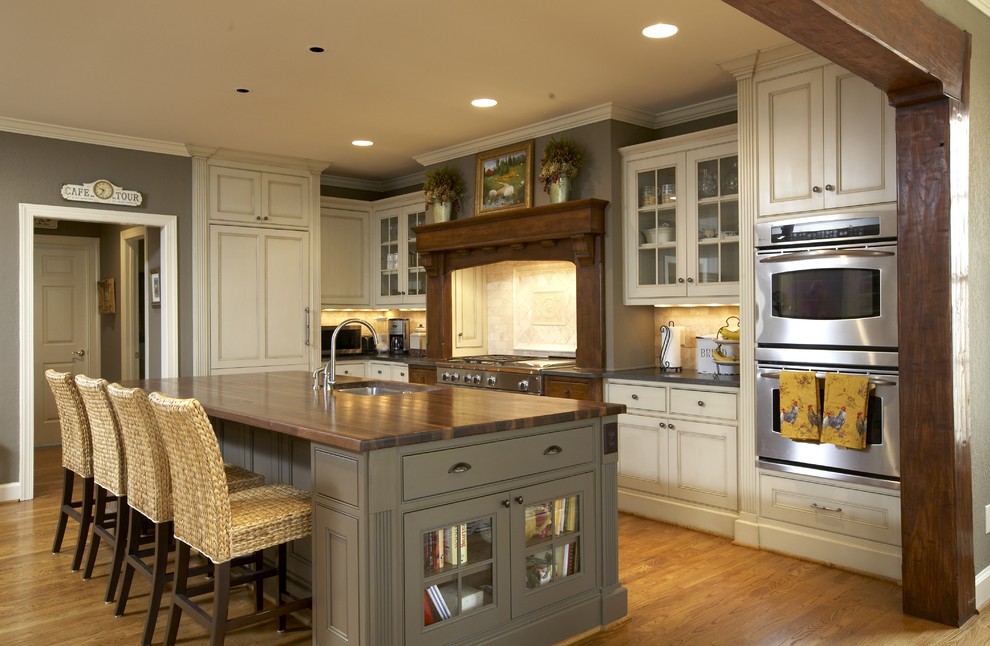 Ejemplo de cocina clásica de obra con armarios con rebordes decorativos, electrodomésticos con paneles, encimera de madera, puertas de armario beige y encimeras marrones