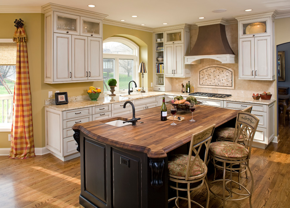 Elegant kitchen photo in Minneapolis with an undermount sink, raised-panel cabinets, white cabinets, wood countertops and beige backsplash