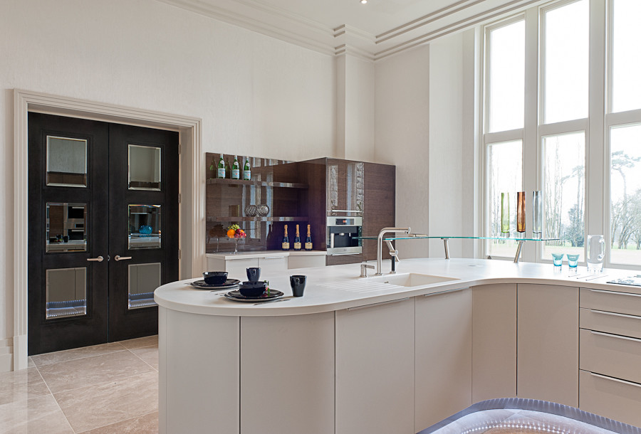 Geräumige Moderne Wohnküche mit integriertem Waschbecken, flächenbündigen Schrankfronten, beigen Schränken, Küchengeräten aus Edelstahl, Porzellan-Bodenfliesen und Kücheninsel in London