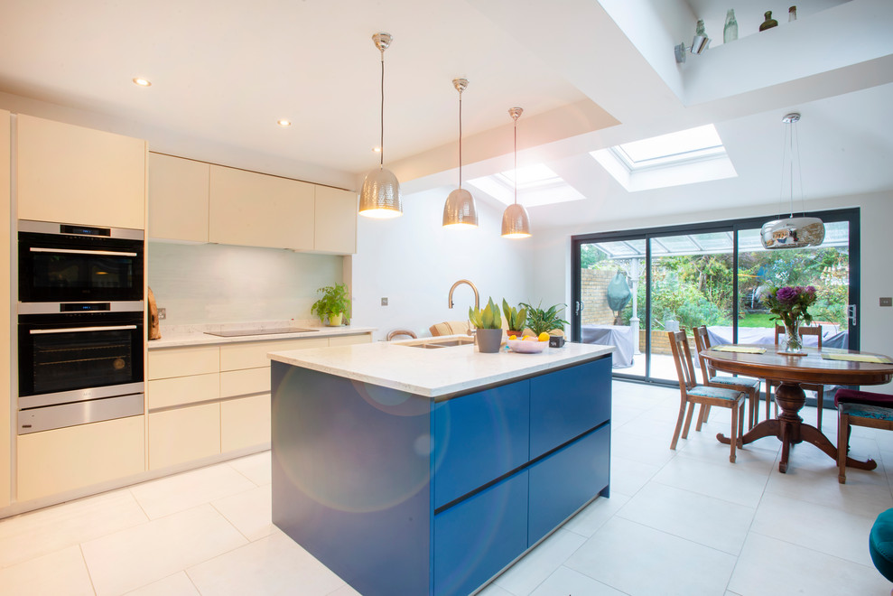 Medium sized urban single-wall open plan kitchen in London with a double-bowl sink, louvered cabinets, white cabinets, an island, white floors and white worktops.
