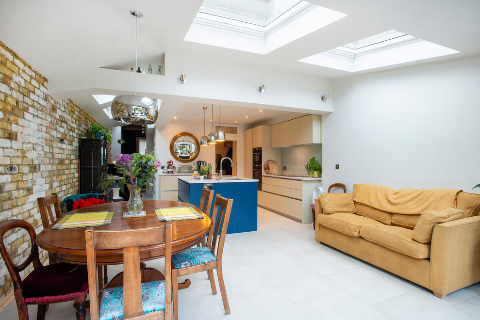 This is an example of a medium sized urban single-wall open plan kitchen in London with a double-bowl sink, louvered cabinets, white cabinets, an island, white floors and white worktops.