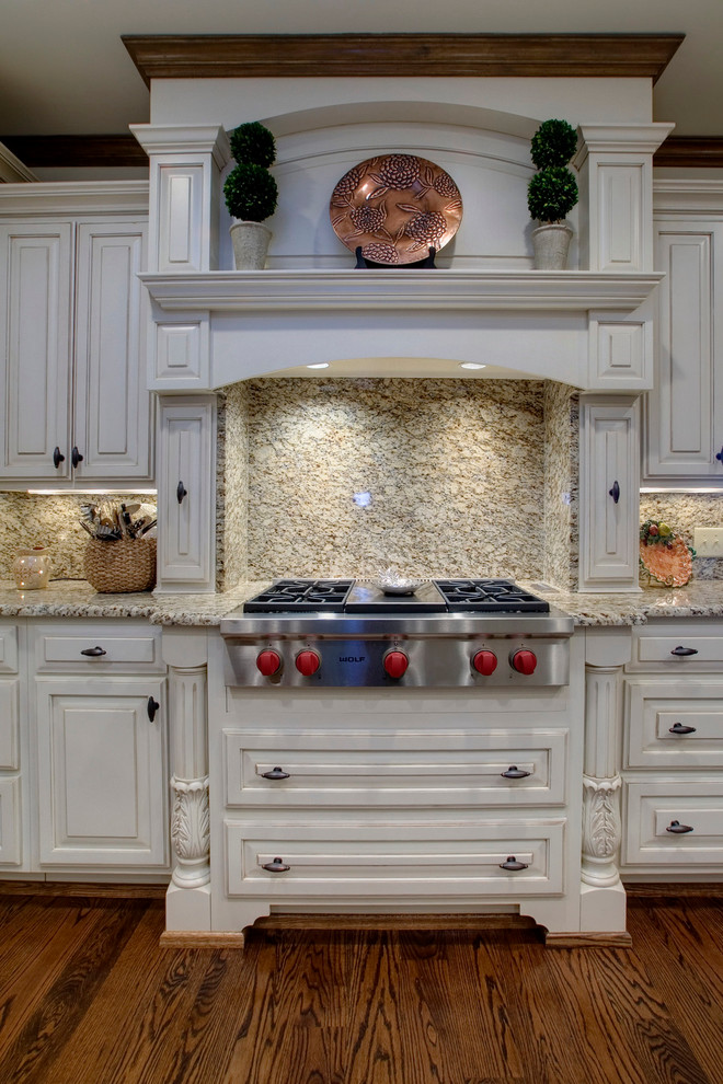 Inspiration for a timeless u-shaped eat-in kitchen remodel in Nashville with an undermount sink, raised-panel cabinets, distressed cabinets, granite countertops, multicolored backsplash and stainless steel appliances