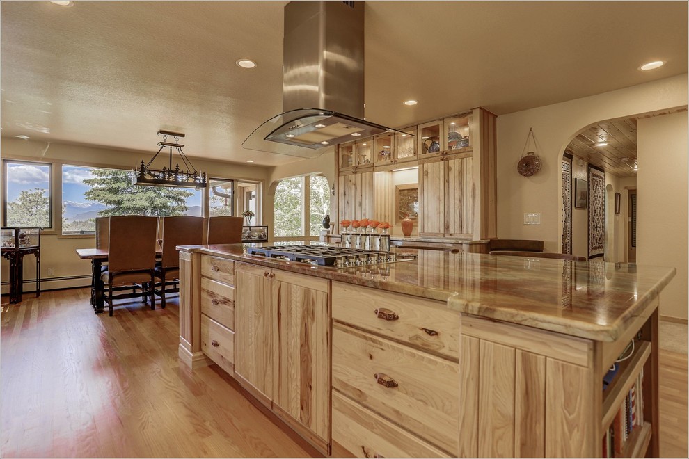 This is an example of an expansive rustic l-shaped kitchen/diner in Denver with louvered cabinets, medium wood cabinets, an island, a belfast sink and stainless steel appliances.