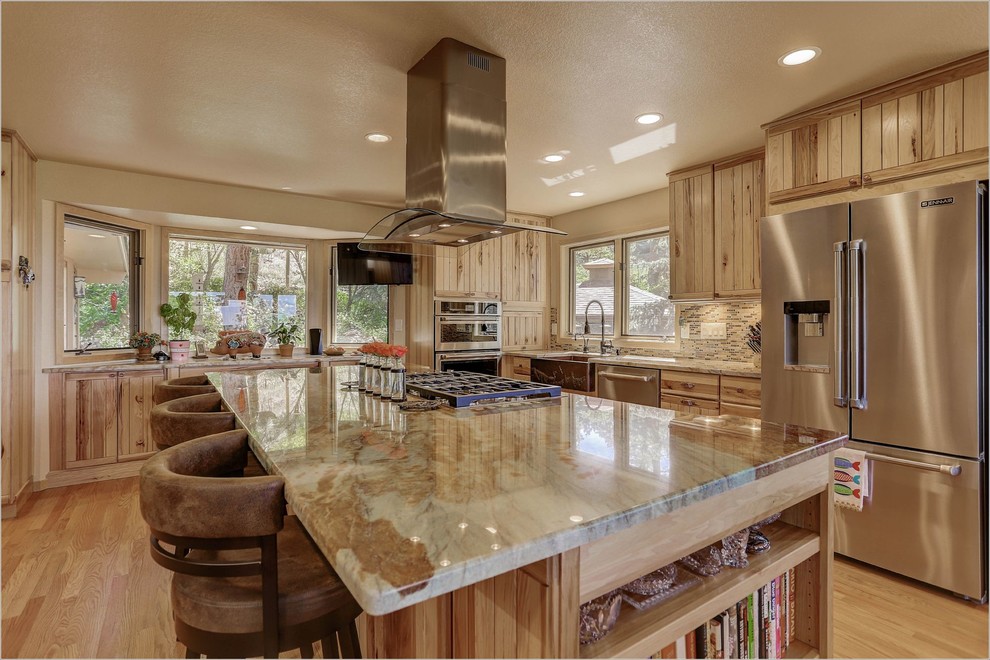 Inspiration for an expansive rustic l-shaped kitchen/diner in Denver with a belfast sink, louvered cabinets, medium wood cabinets, stainless steel appliances and an island.