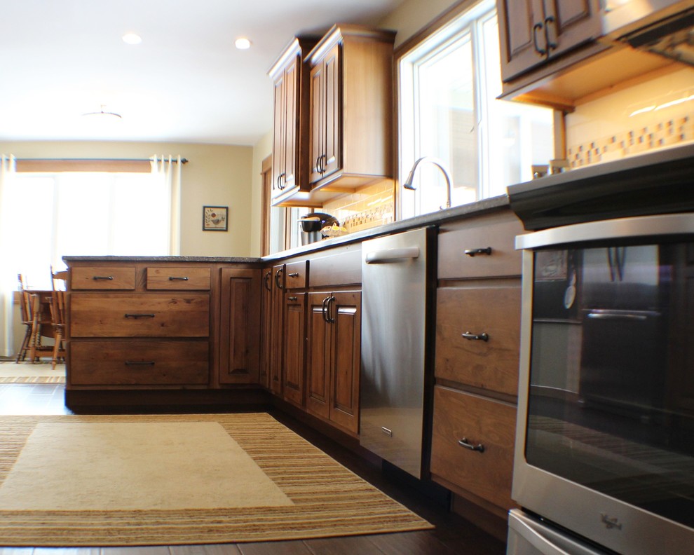Bild på ett mellanstort vintage kök och matrum, med en undermonterad diskho, luckor med upphöjd panel, skåp i mellenmörkt trä, bänkskiva i kvarts, beige stänkskydd, stänkskydd i tunnelbanekakel, rostfria vitvaror, mörkt trägolv och en halv köksö