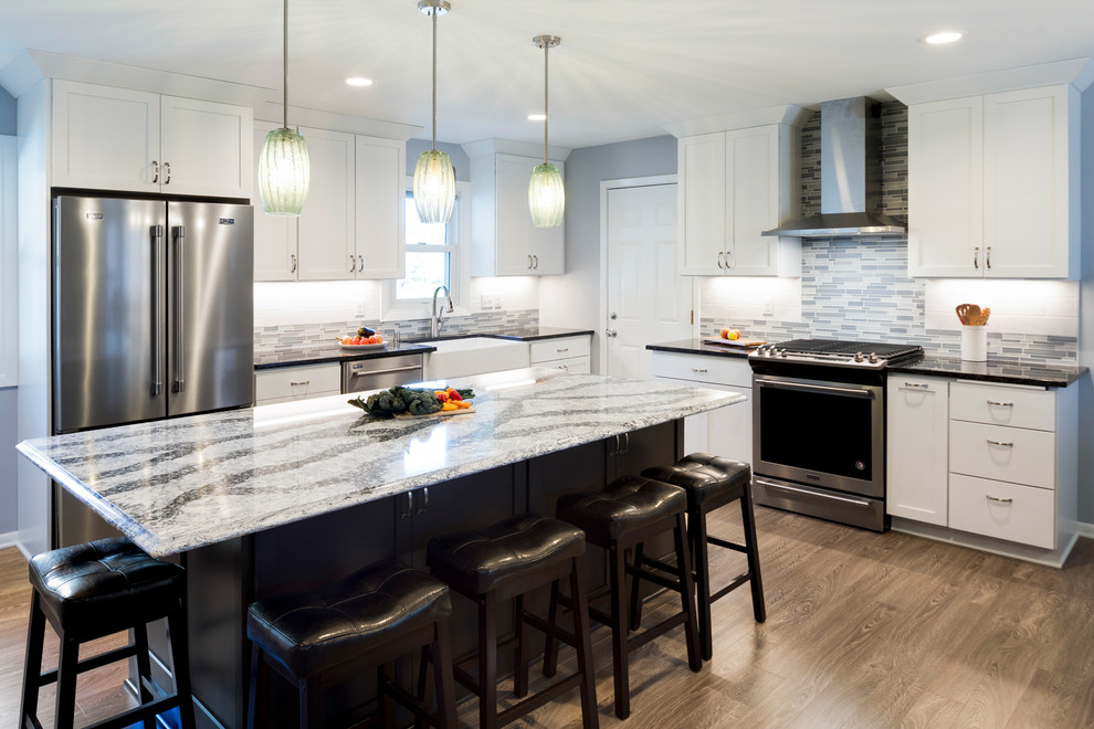 Huge elegant l-shaped laminate floor and gray floor eat-in kitchen photo in Minneapolis with a farmhouse sink, recessed-panel cabinets, white cabinets, quartz countertops, multicolored backsplash, glass tile backsplash, stainless steel appliances and an island