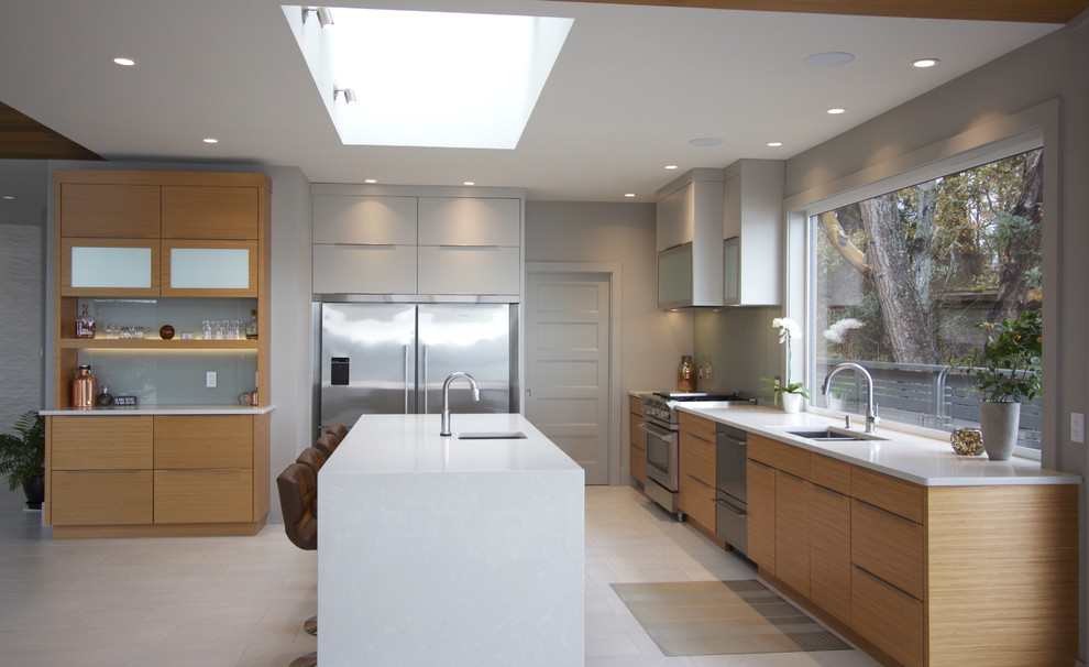 This is an example of a large modern galley kitchen/diner in Vancouver with a submerged sink, flat-panel cabinets, light wood cabinets, engineered stone countertops, stainless steel appliances, porcelain flooring, an island, white floors and white worktops.