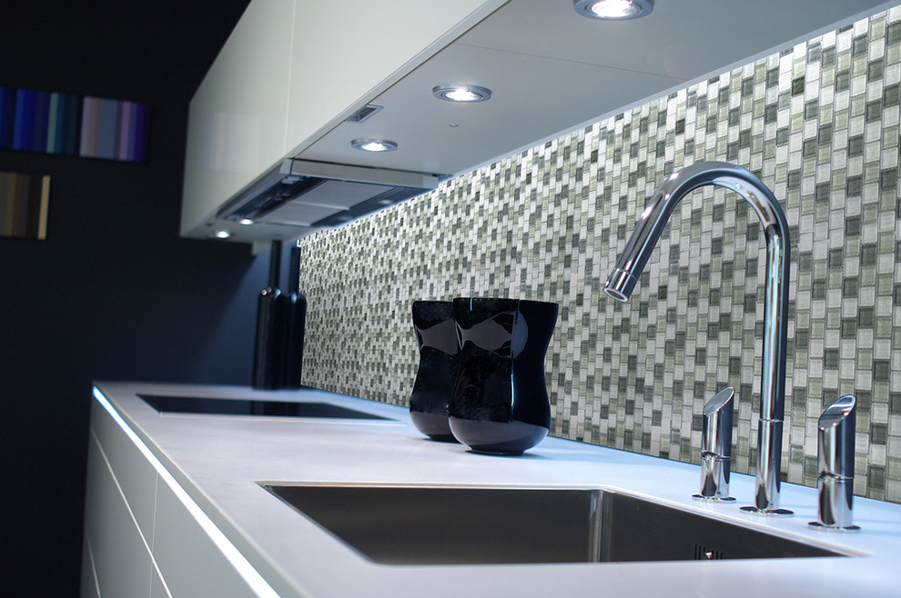 Immagine di una cucina lineare contemporanea chiusa e di medie dimensioni con lavello da incasso, ante lisce, ante bianche, top in vetro, paraspruzzi multicolore e paraspruzzi con piastrelle a mosaico