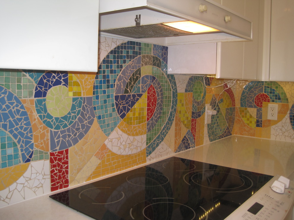 Modern inredning av ett mellanstort l-kök, med en dubbel diskho, släta luckor, vita skåp, stänkskydd i mosaik, vita vitvaror och klinkergolv i keramik
