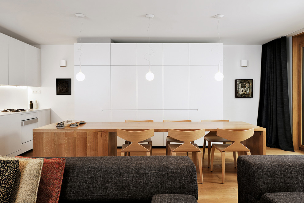 Ejemplo de cocinas en L contemporánea abierta con armarios con paneles lisos, puertas de armario blancas, electrodomésticos blancos y suelo de madera en tonos medios