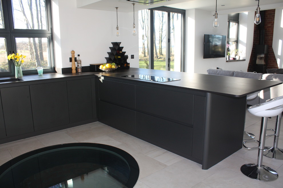 Photo of a medium sized modern u-shaped open plan kitchen in Other with a breakfast bar, a submerged sink, flat-panel cabinets, grey cabinets, composite countertops, grey splashback, black appliances, ceramic flooring, engineered quartz splashback, grey floors, grey worktops and a coffered ceiling.