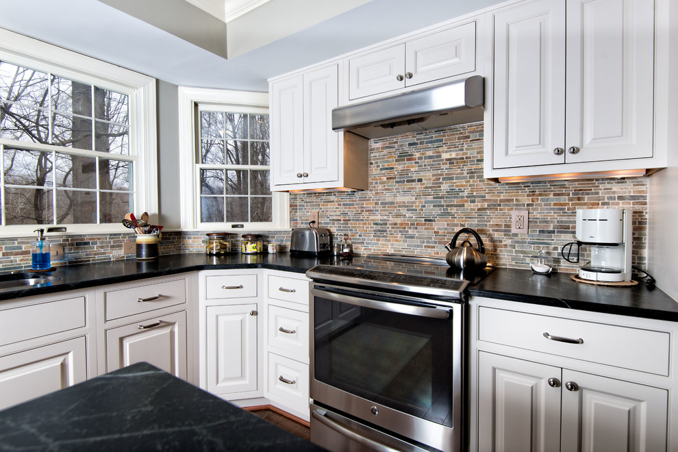 This is an example of a medium sized contemporary u-shaped kitchen in Baltimore with a double-bowl sink, raised-panel cabinets, white cabinets, soapstone worktops, multi-coloured splashback, terracotta splashback, stainless steel appliances, medium hardwood flooring and an island.