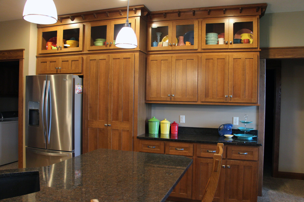 Foto de cocina de estilo americano de tamaño medio con armarios con paneles lisos, puertas de armario de madera oscura, encimera de cuarzo compacto, electrodomésticos de acero inoxidable y una isla
