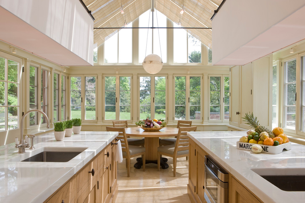 Réalisation d'une cuisine américaine tradition en bois clair avec un évier encastré, un placard avec porte à panneau encastré, plan de travail en marbre et un électroménager en acier inoxydable.