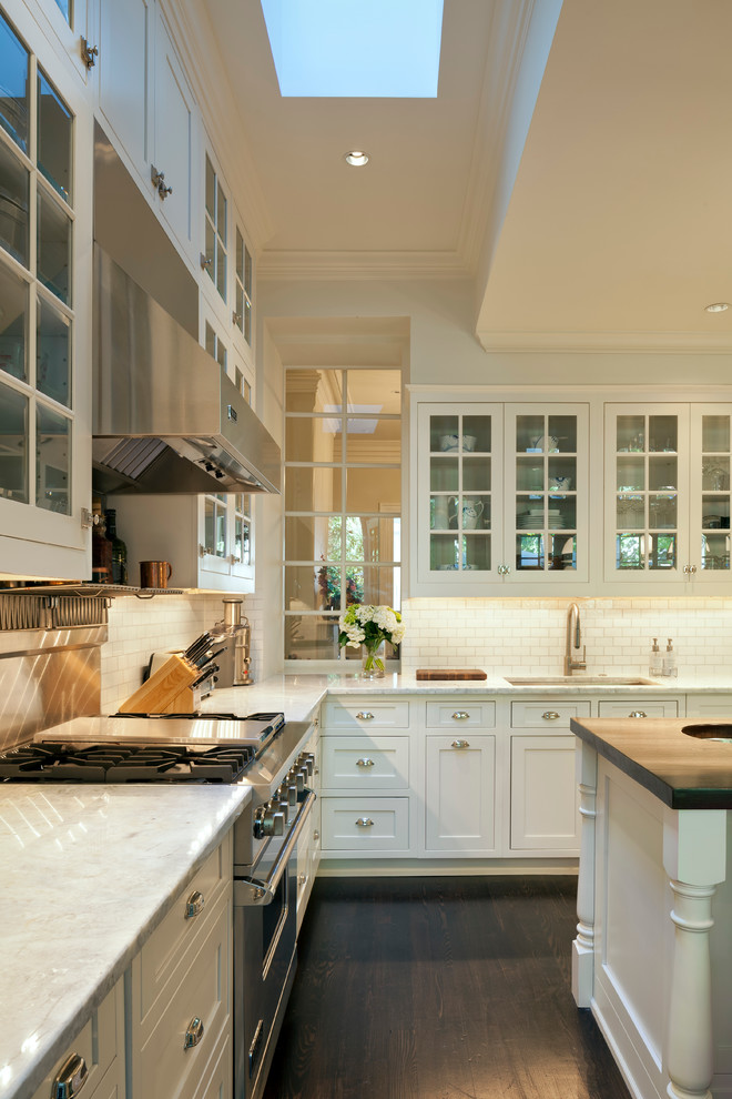 ワシントンD.C.にあるトラディショナルスタイルのおしゃれなキッチン (ガラス扉のキャビネット、白いキャビネット、大理石カウンター、白いキッチンパネル、セラミックタイルのキッチンパネル、シルバーの調理設備、濃色無垢フローリング) の写真
