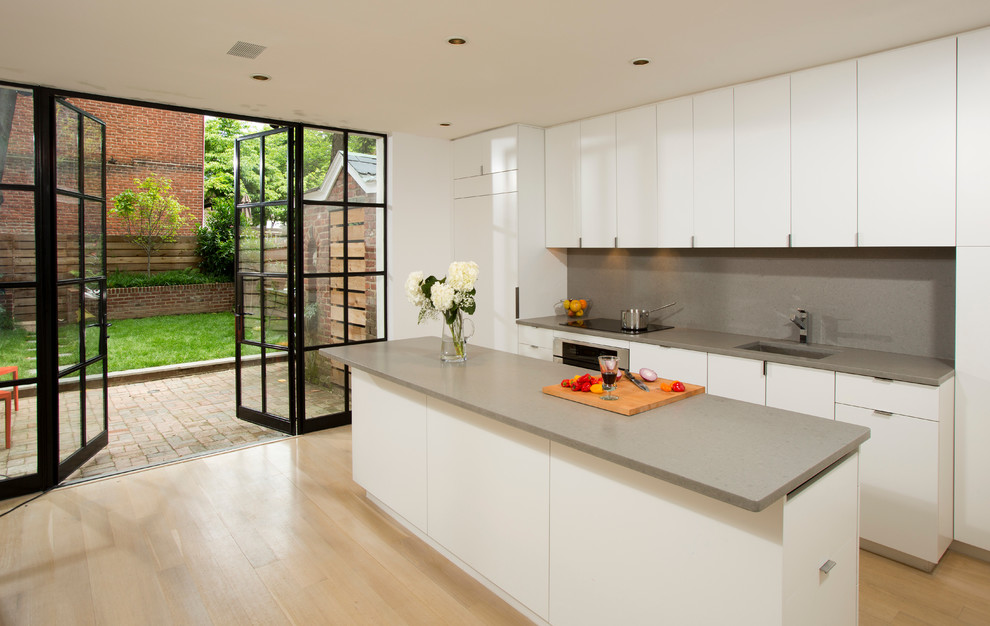 Источник вдохновения для домашнего уюта: прямая кухня в современном стиле с плоскими фасадами, белыми фасадами, серым фартуком и техникой под мебельный фасад
