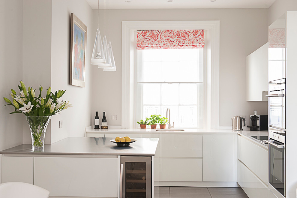 Trendy l-shaped kitchen photo in Kent with an undermount sink, flat-panel cabinets, white cabinets, stainless steel appliances and a peninsula