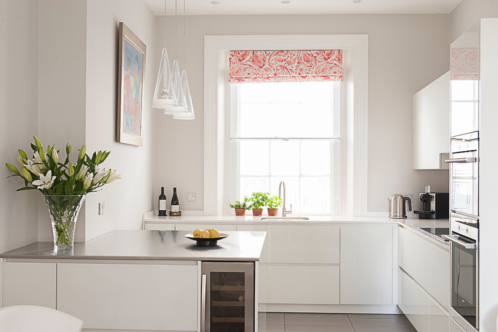 Moderne Küche in L-Form mit Unterbauwaschbecken, flächenbündigen Schrankfronten, weißen Schränken, Küchengeräten aus Edelstahl und Halbinsel in Kent