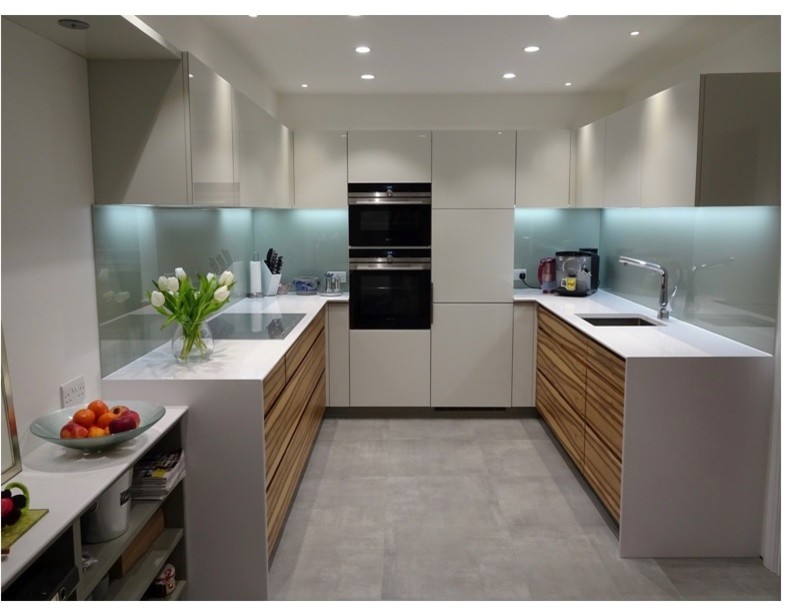 Photo of a small modern u-shaped kitchen/diner in Other with an integrated sink, grey cabinets, composite countertops, grey splashback, glass sheet splashback, black appliances and ceramic flooring.