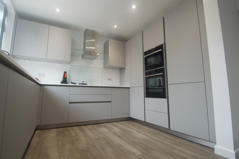 Moderne Wohnküche ohne Insel in U-Form mit grauen Schränken und Küchengeräten aus Edelstahl in Manchester