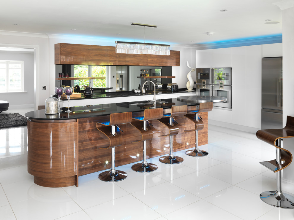 Large contemporary l-shaped open plan kitchen in London with a double-bowl sink, flat-panel cabinets, dark wood cabinets, granite worktops, metallic splashback, mirror splashback, stainless steel appliances, ceramic flooring and an island.