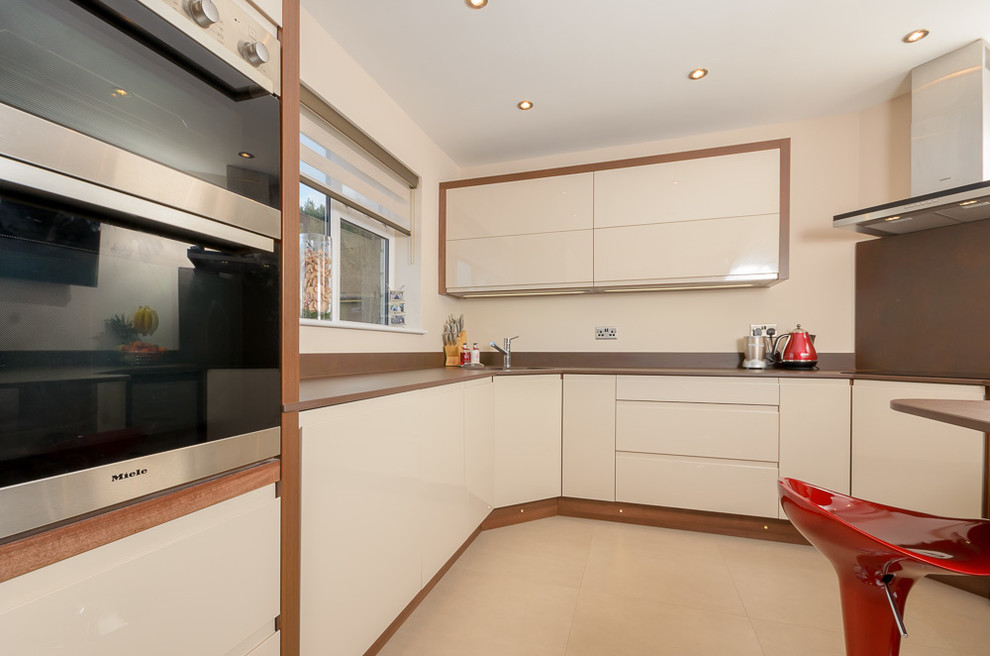 Bild på ett litet funkis kök, med en undermonterad diskho, släta luckor, skåp i ljust trä, bänkskiva i kvarts, brunt stänkskydd, integrerade vitvaror, linoleumgolv och en halv köksö