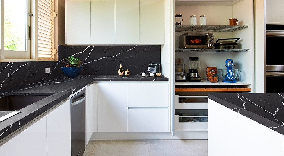 This is an example of a country kitchen in London with quartz worktops and black worktops.
