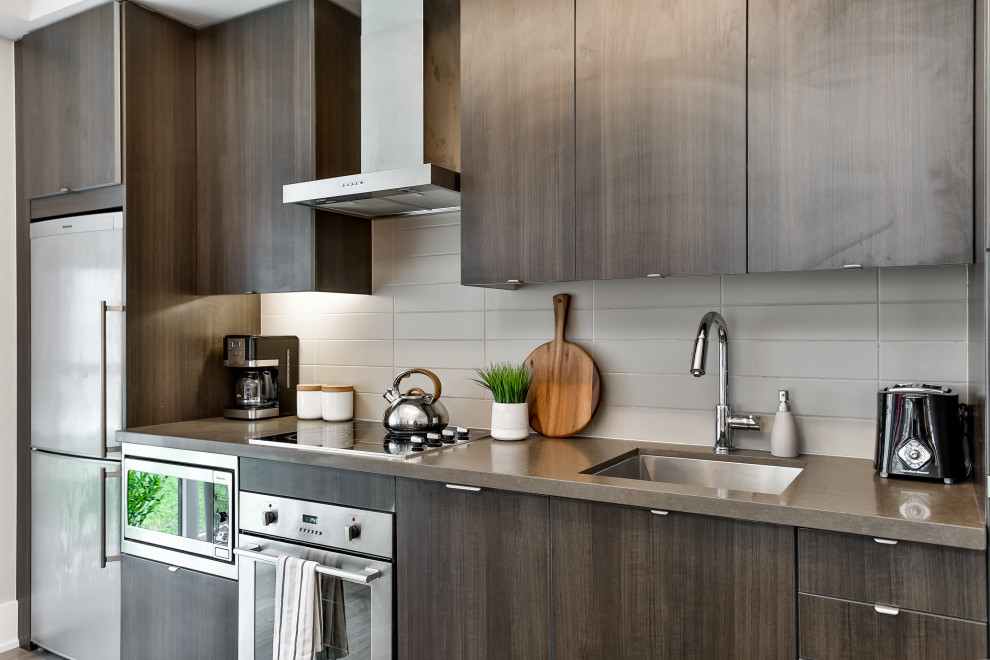 Inspiration for a mid-sized contemporary single-wall kitchen remodel in Toronto with an undermount sink, flat-panel cabinets, medium tone wood cabinets, white backsplash, porcelain backsplash, stainless steel appliances, no island and gray countertops
