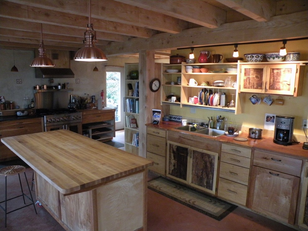 This is an example of a small farmhouse l-shaped enclosed kitchen in Burlington with a double-bowl sink, shaker cabinets, light wood cabinets, wood worktops, stainless steel appliances, concrete flooring and an island.
