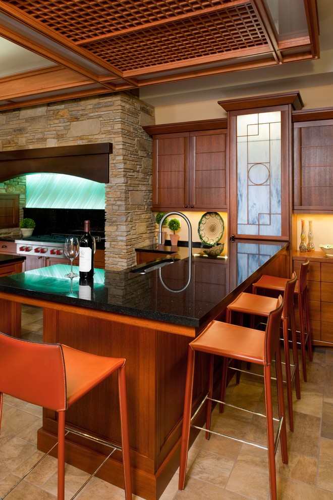 Bild på ett stort, avskilt orientaliskt u-kök, med en undermonterad diskho, luckor med infälld panel, skåp i mellenmörkt trä, rostfria vitvaror, klinkergolv i keramik, granitbänkskiva, grönt stänkskydd, stänkskydd i keramik, en köksö och brunt golv