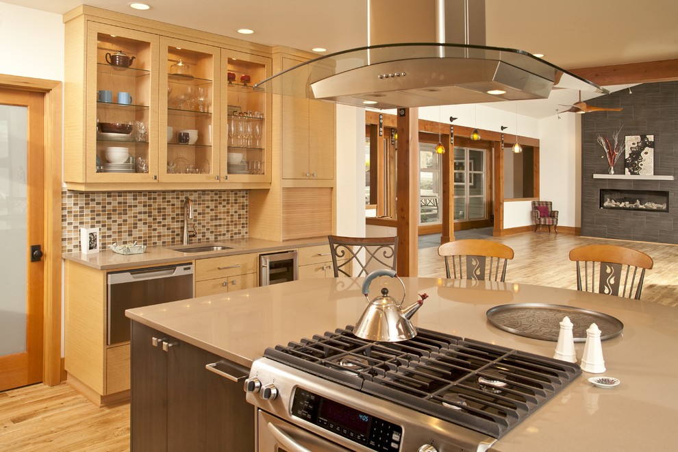 Inspiration for a zen l-shaped light wood floor open concept kitchen remodel in Seattle with flat-panel cabinets, light wood cabinets, solid surface countertops, multicolored backsplash, mosaic tile backsplash, stainless steel appliances, an island and a double-bowl sink