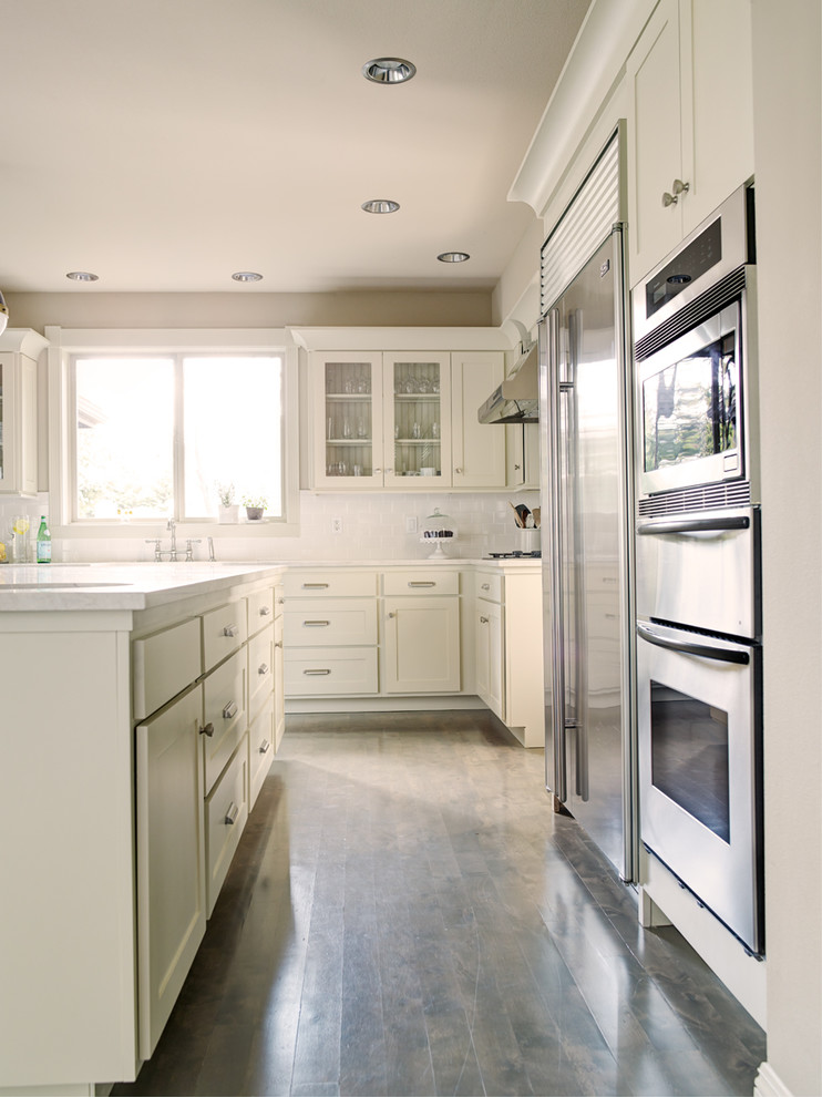Mid-sized transitional l-shaped light wood floor eat-in kitchen photo in Seattle with shaker cabinets, white cabinets, quartzite countertops, white backsplash, subway tile backsplash, stainless steel appliances, an island and a farmhouse sink