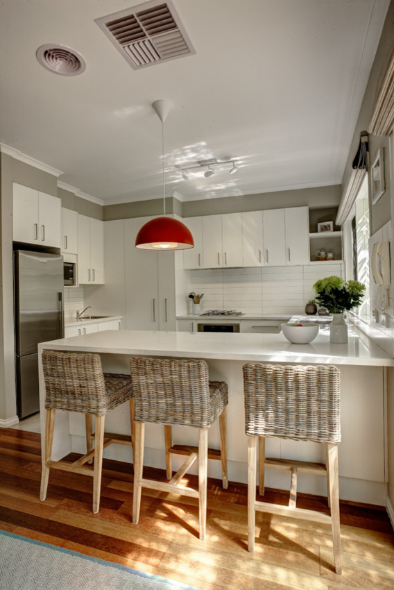 Design ideas for a medium sized contemporary u-shaped kitchen/diner in Melbourne with a double-bowl sink, flat-panel cabinets, white cabinets, engineered stone countertops, white splashback, ceramic splashback, stainless steel appliances, porcelain flooring and a breakfast bar.
