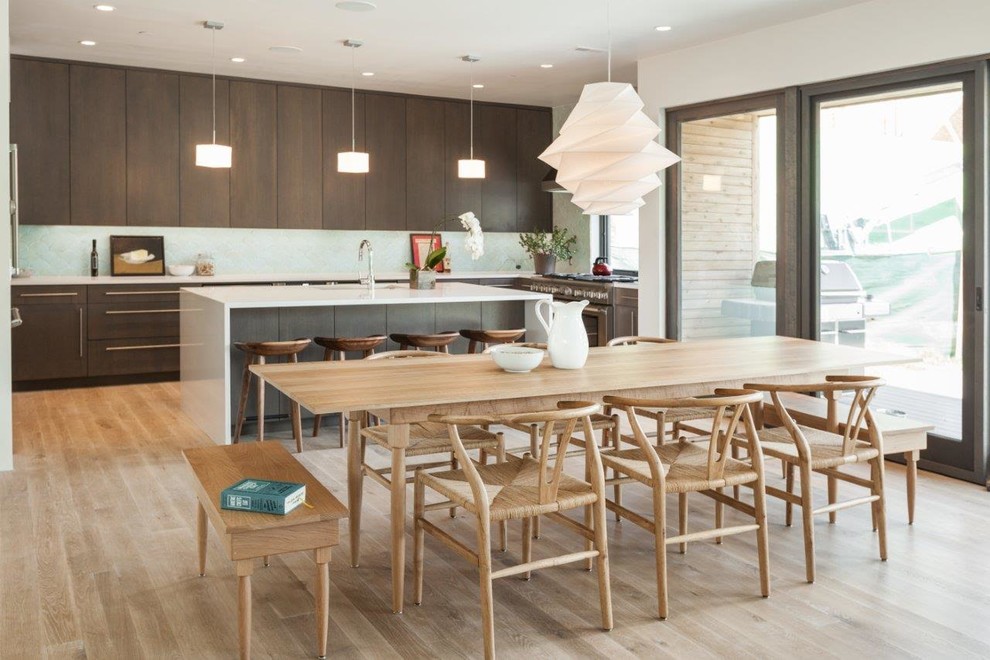 Inspiration for a large modern u-shaped kitchen/diner in Other with flat-panel cabinets, brown cabinets, blue splashback, stainless steel appliances, light hardwood flooring, an island and brown floors.